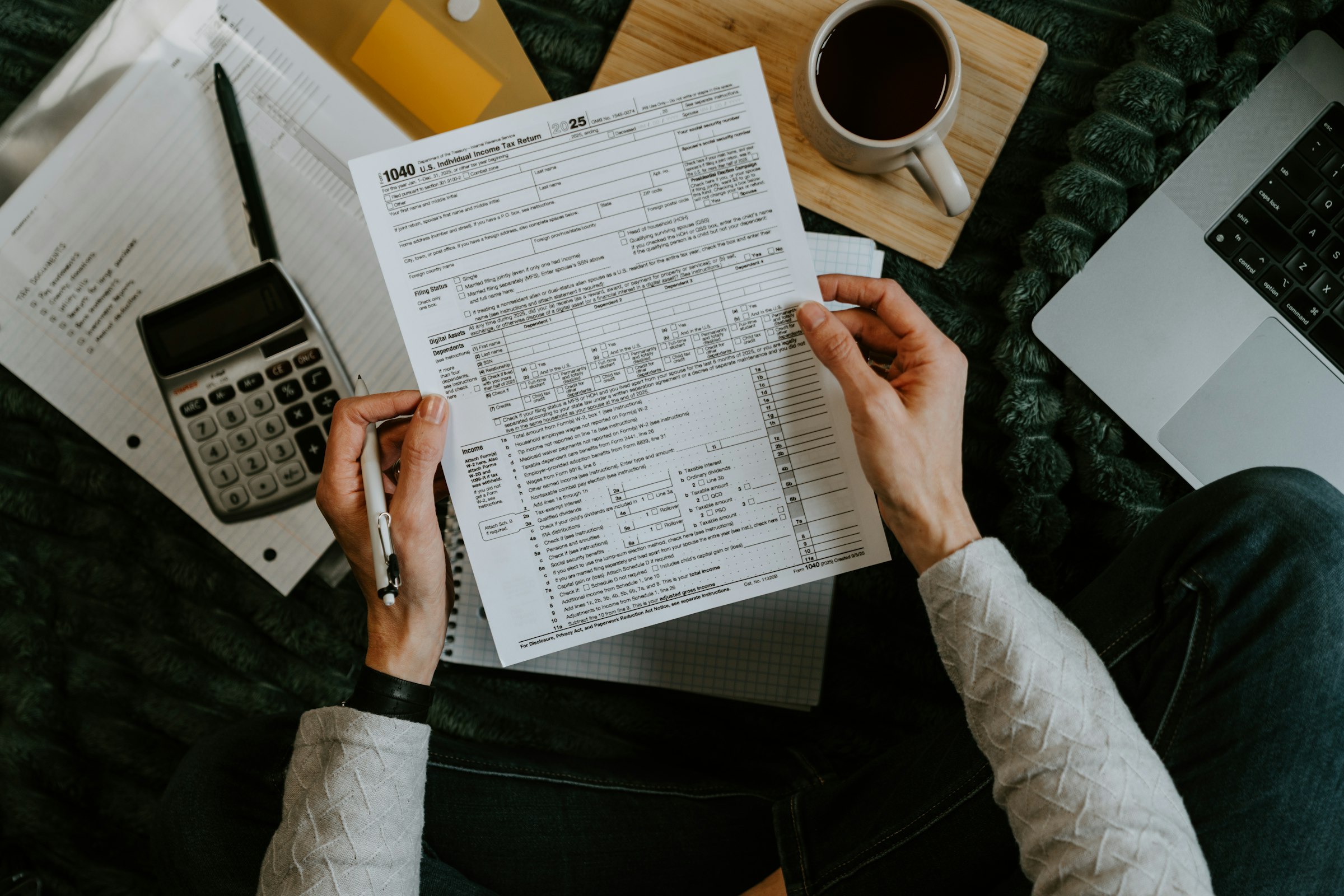 Dark slate desk with tax documents, calculator, and financial records